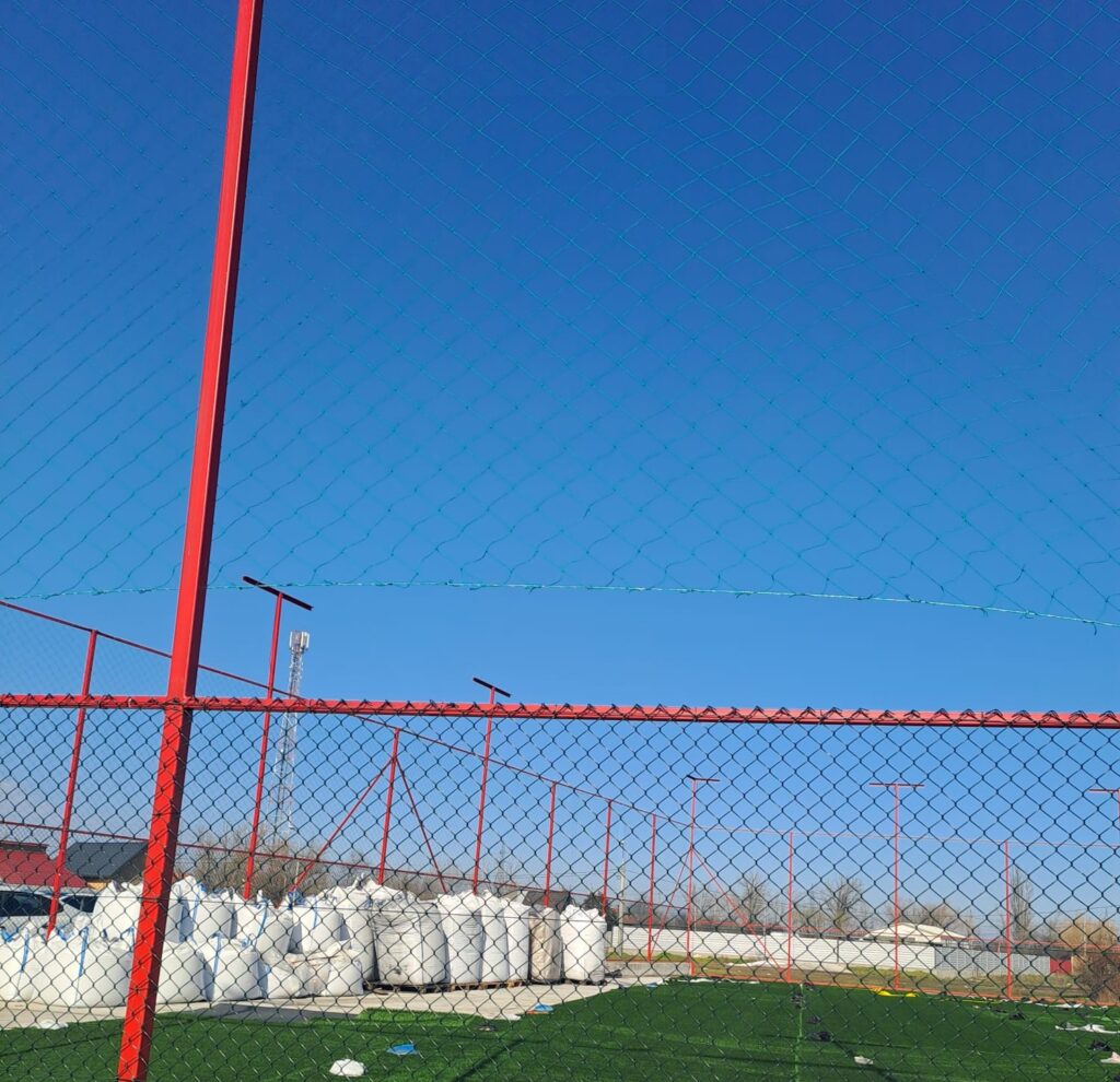 Teren de fotbal împrejmuit și parțial acoperit cu plasă verde
