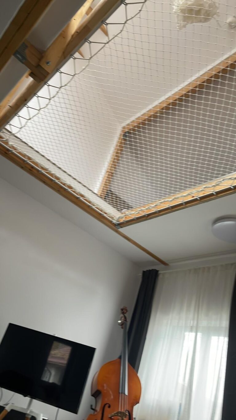 Plasă albă de siguranță montată pe ramă de lemn sub un pod interior, văzută de jos